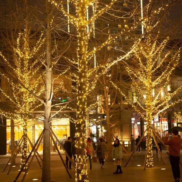 Warm white IP65 LED string lights wrapped around trees in an outdoor commercial plaza