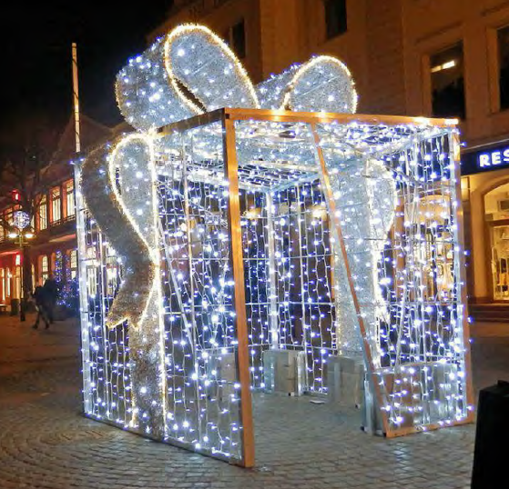 Open-frame illuminated gift pavilion with light curtain walls and large ribbon bow