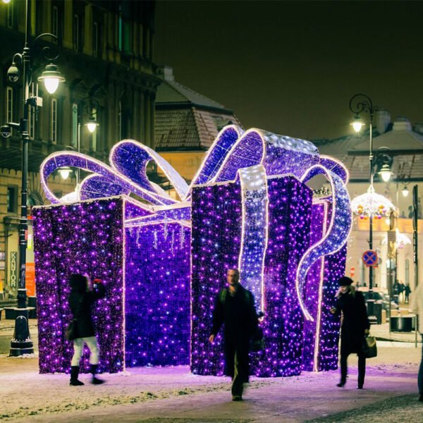 Open-sided giant illuminated present with broad curling ribbons in a winter pedestrian square