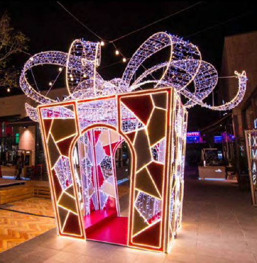 Gift-shaped illuminated portal with angular panel decoration and oversized curling bow
