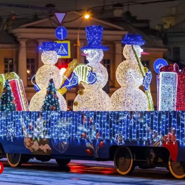 Three illuminated snowmen with blue hats, including an accordion player, arranged on a festive display platform