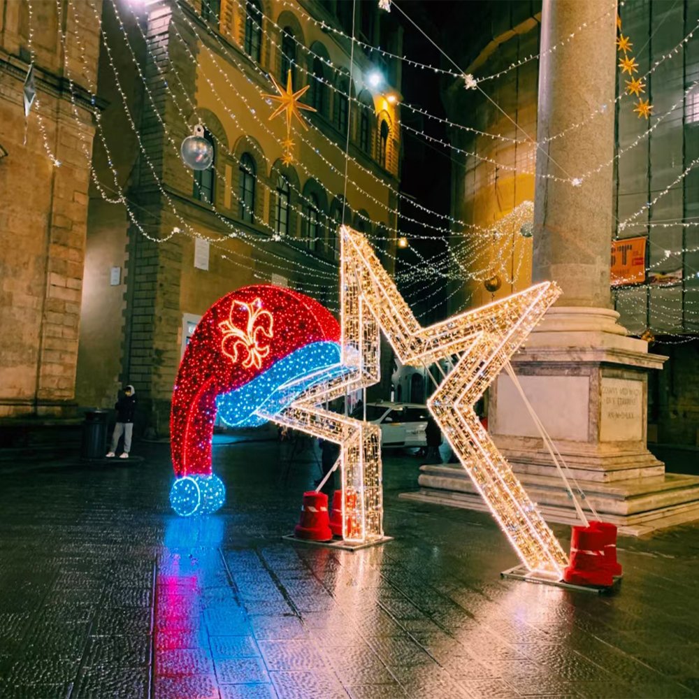 Open illuminated star frame beside a decorative Santa hat in a Christmas streetscape