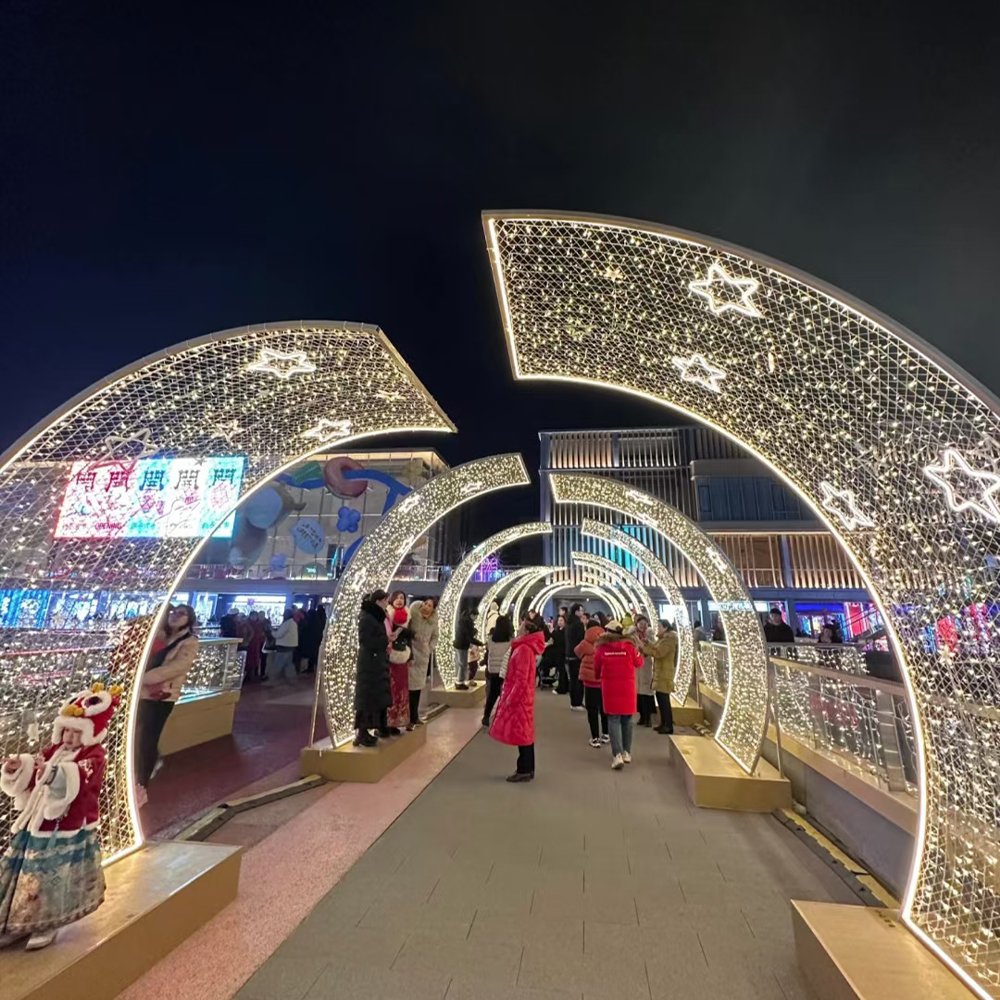 Separated curved light panels with star outlines and open gaps above a pedestrian bridge