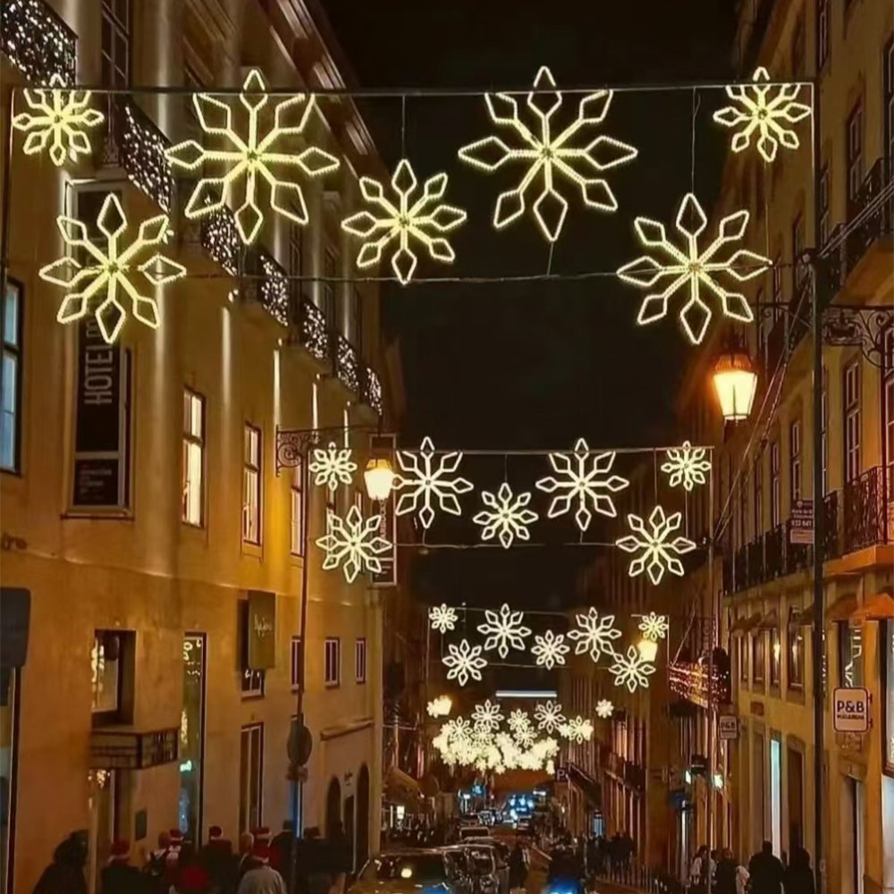 Mixed-size geometric snowflake outline lights suspended across an old-town street