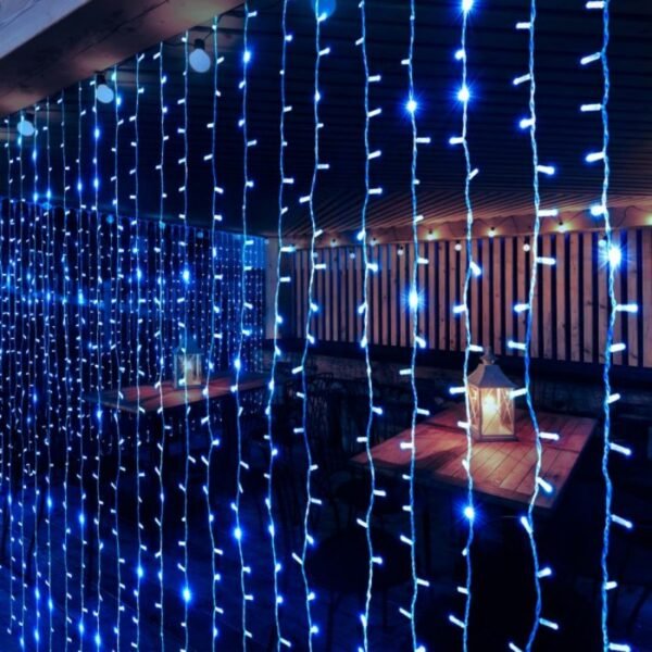 Blue curtain light strands in front of wooden dining tables and lanterns beneath a covered timber deck