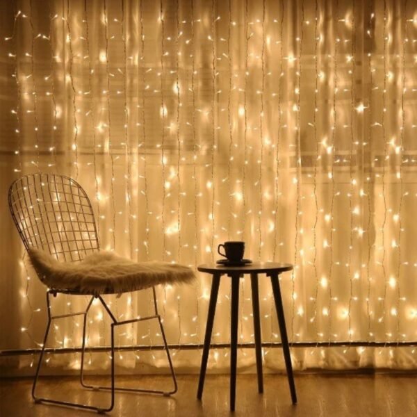 Warm white curtain lights behind a wire chair and small round table with a cup in a reading corner