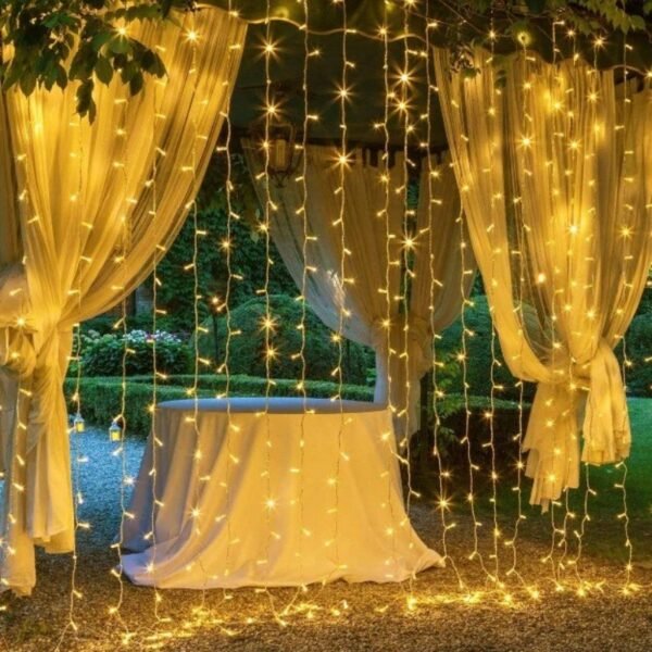 Warm white curtain strands framing tied-back sheer garden drapes and a cloth-covered reception table