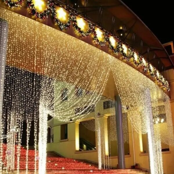 Warm white light canopy and long vertical curtain drops framing a building entrance beneath festive garlands