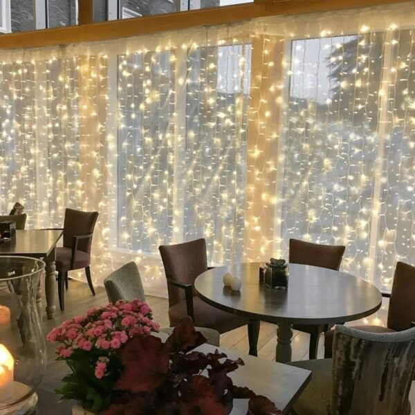 Warm white curtain string lights hanging across tall windows behind café tables and chairs