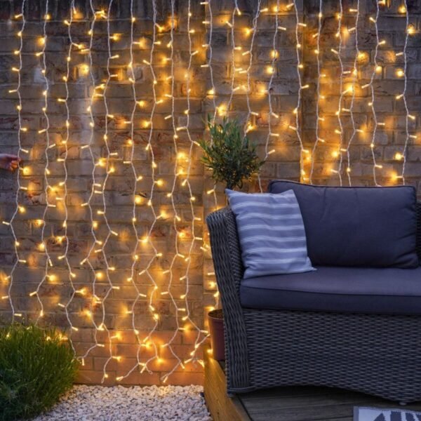 Warm white LED curtain lights with transparent cable hanging against a brick wall behind terrace seating