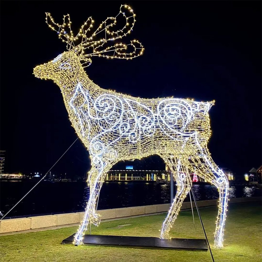 Standing illuminated deer with curling antlers and contrasting scrollwork patterns across its body on a lawn