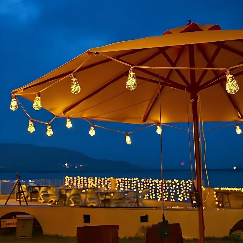 Warm pear Edison lamps following the edge of a large parasol above a waterfront hospitality terrace