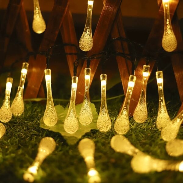 Warm white waterdrop-shaped lights hanging beside a timber lattice with greenery in the foreground