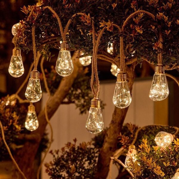 Warm pear-shaped Edison pendant lights hanging at different heights among branches and dense foliage