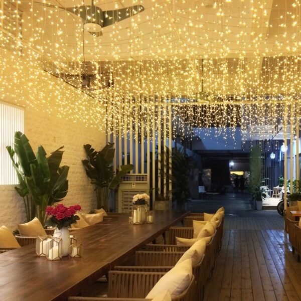 Warm white icicle light canopy above a restaurant seating area